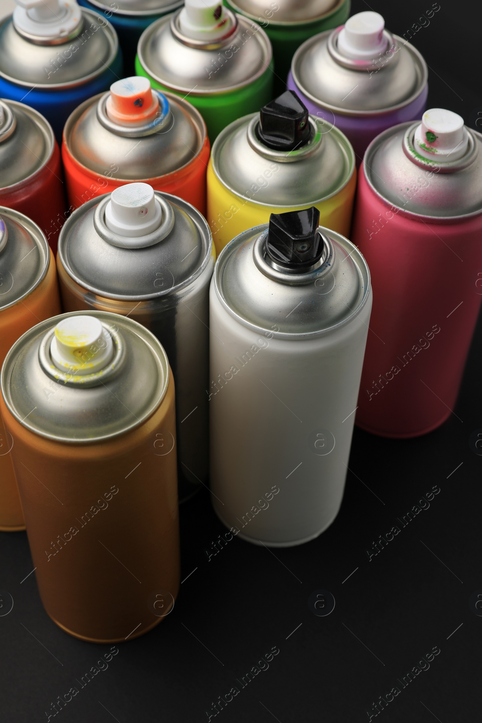 Photo of Cans of different graffiti spray paints on black background