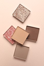 Different beautiful eye shadows on beige background, flat lay