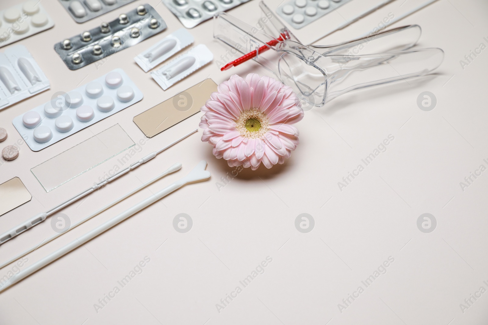 Photo of Sterile gynecological tools, pills and gerbera flower on beige background. Space for text