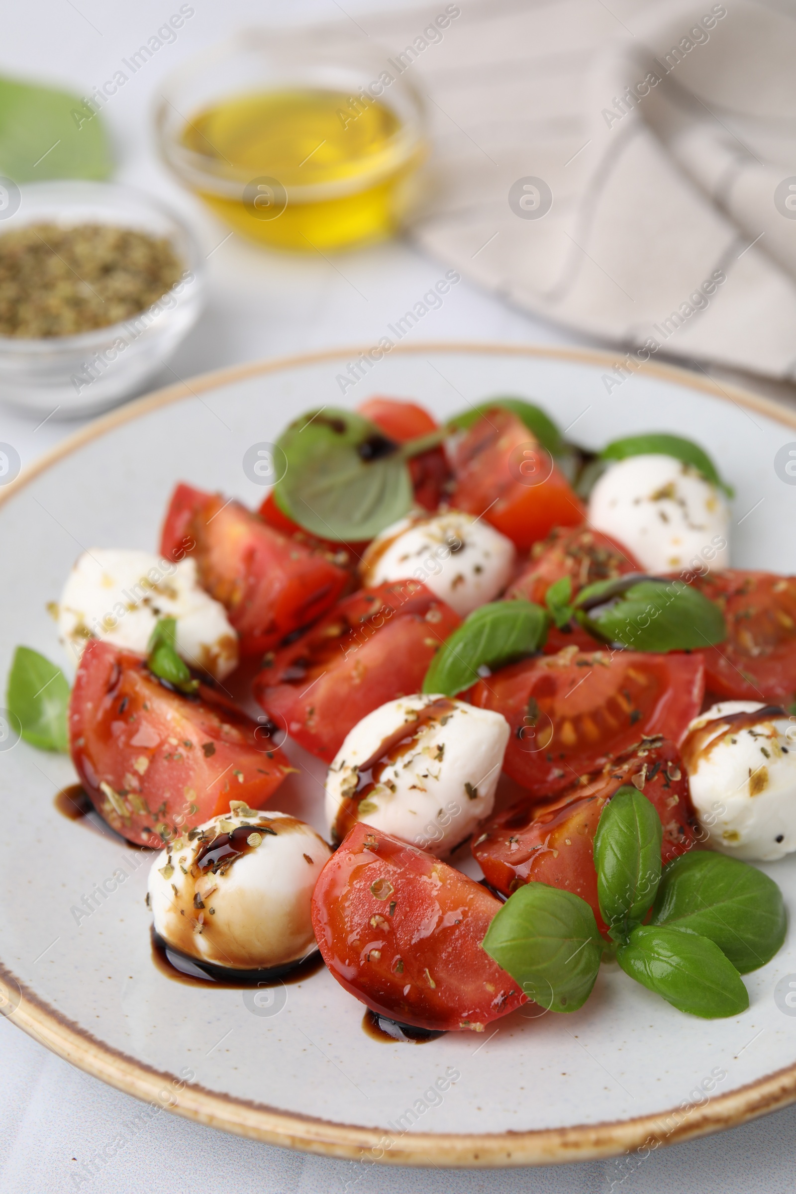 Photo of Tasty salad Caprese with mozarella balls, tomatoes, basil and sauce on table, closeup