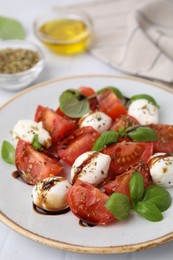 Photo of Tasty salad Caprese with mozarella balls, tomatoes, basil and sauce on table, closeup