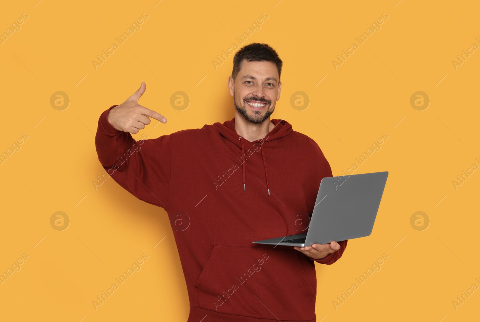 Photo of Happy man with laptop on orange background