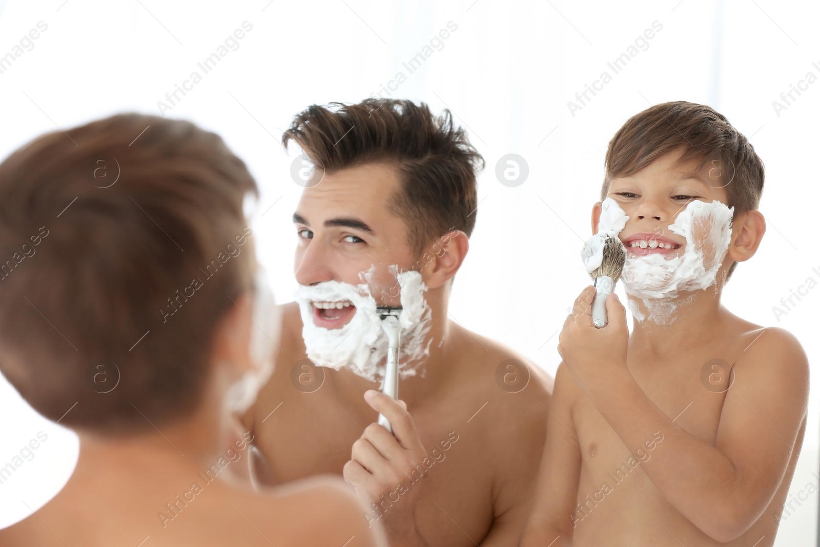 Photo of Father and son having fun while shaving in bathroom