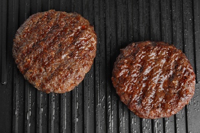 Photo of Prepared meat cutlets for burger on grill, top view