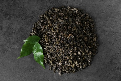 Photo of Heap of dried green tea leaves on grey table, top view