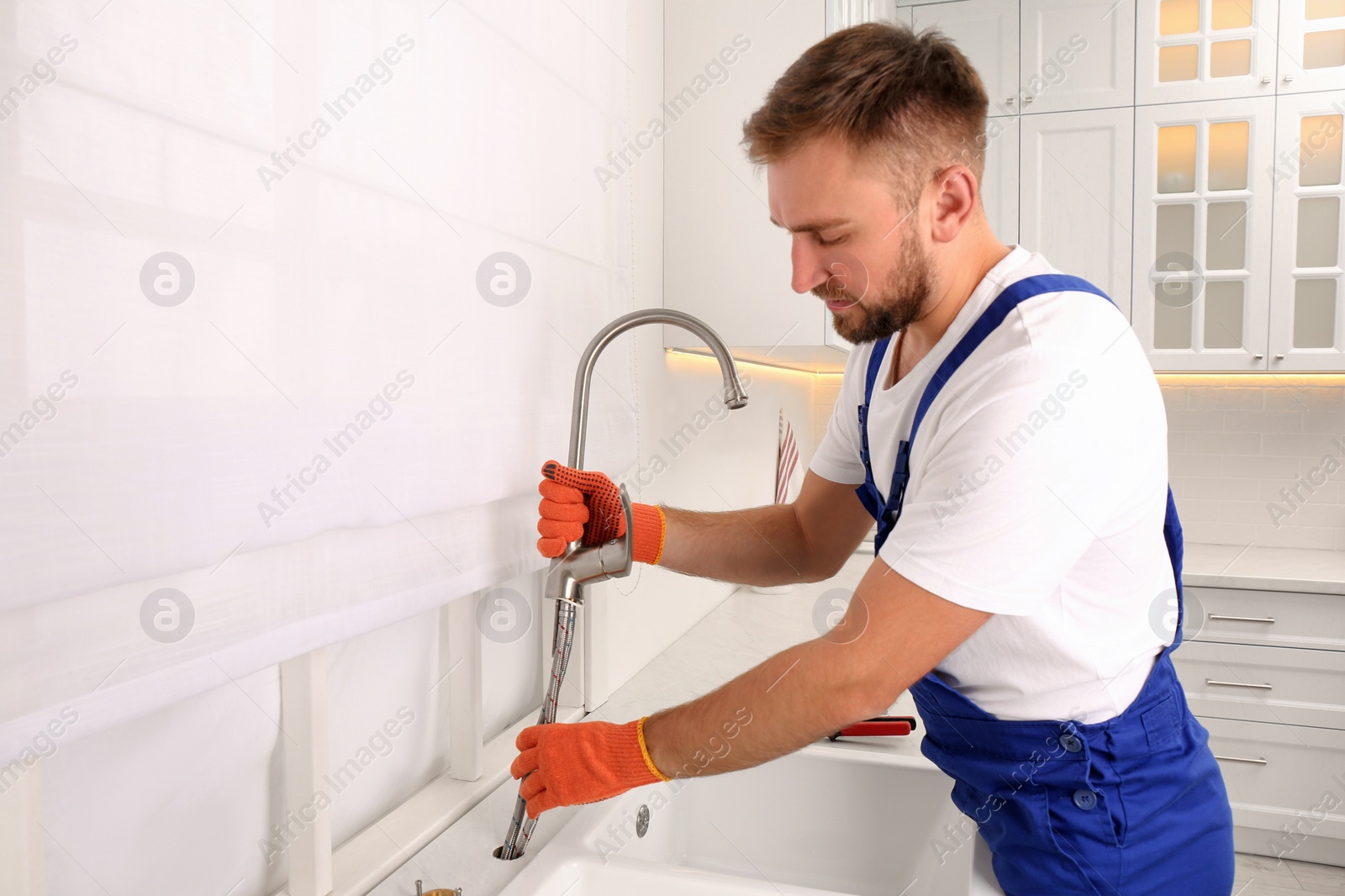 Photo of Professional plumber repairing water tap in kitchen