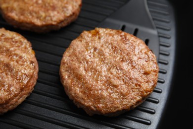 Photo of Tasty fried hamburger patties on grill pan, closeup
