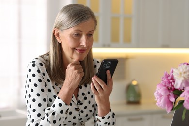 Senior woman using mobile phone at home