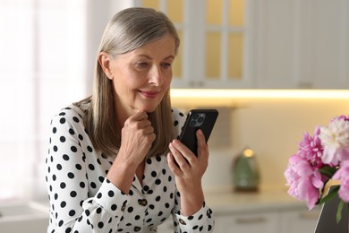 Photo of Senior woman using mobile phone at home