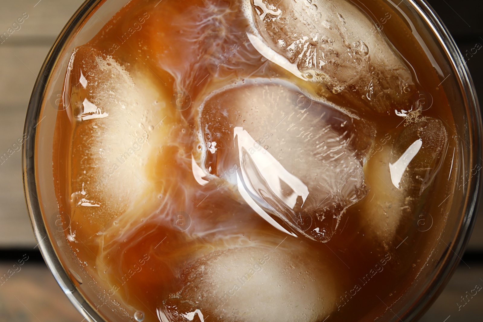 Photo of Coffee with milk and ice cubes in glass, top view