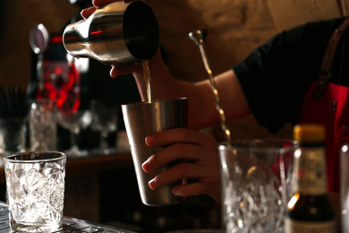 Photo of Bartender preparing fresh alcoholic cocktail at bar counter, closeup