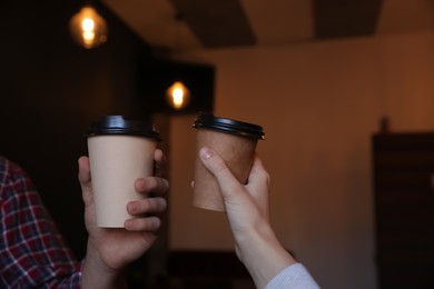 Couple with takeaway coffee cups in cafe, closeup