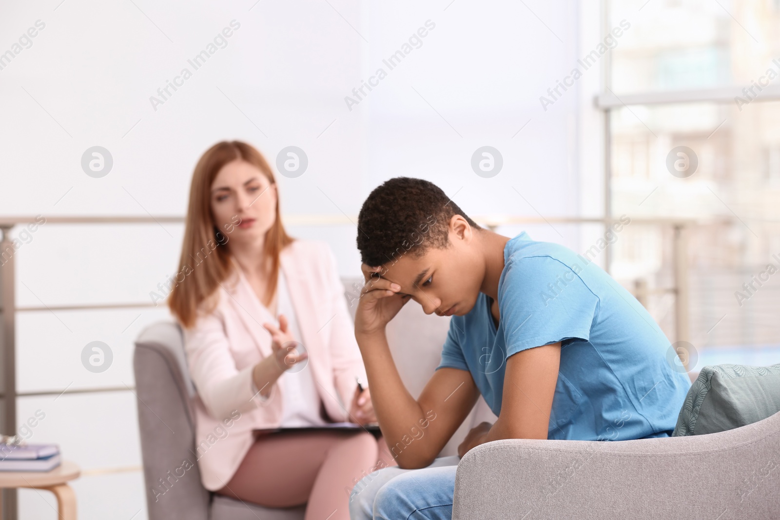 Photo of Young female psychologist working with teenage boy in office