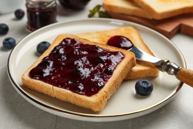 Photo of Toast with blueberry jam, roasted slice of bread and knife on table, closeup