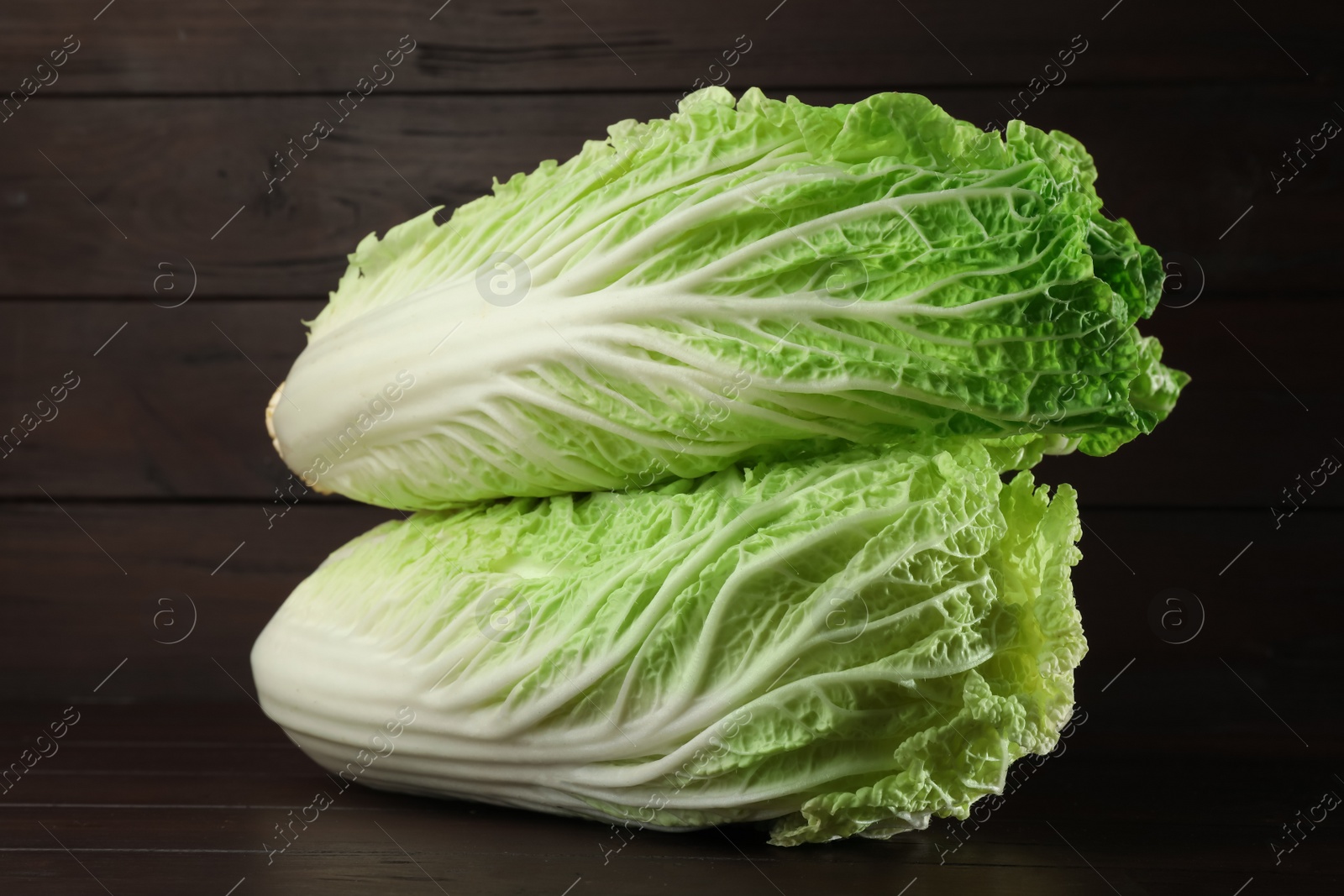 Photo of Fresh ripe Chinese cabbages on table against wooden background