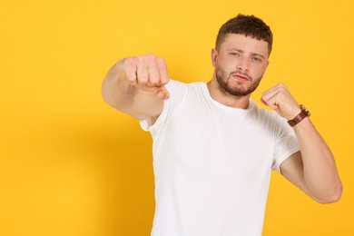 Photo of Young man ready to fight on orange background