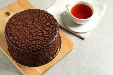 Photo of Delicious chocolate truffle cake and tea on light grey table, space for text