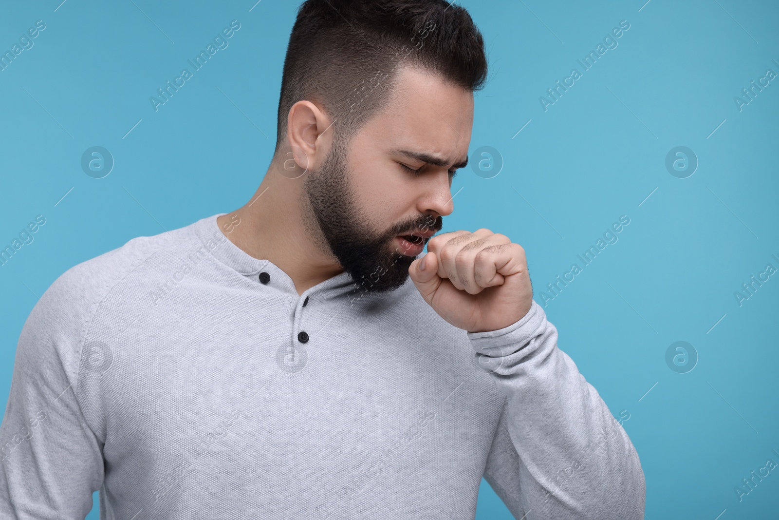 Photo of Sick man coughing on light blue background