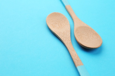 Clean empty bamboo spoons on blue background, space for text