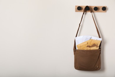 Photo of Brown postman bag with newspapers and mails hanging on light wall, space for text