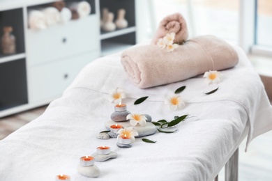 Towels, candles and stones on massage table in spa salon