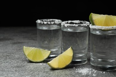 Photo of Mexican Tequila shots with salt and lime slices on grey table
