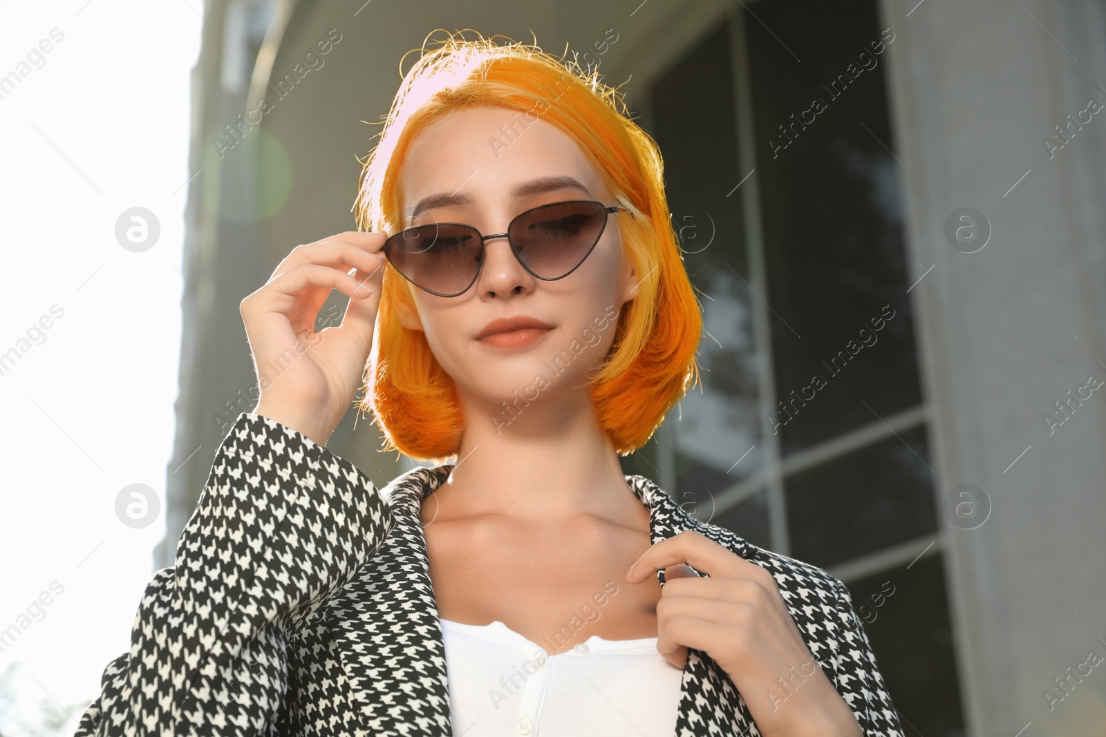 Photo of Beautiful young woman with bright dyed hair in sunglasses outdoors