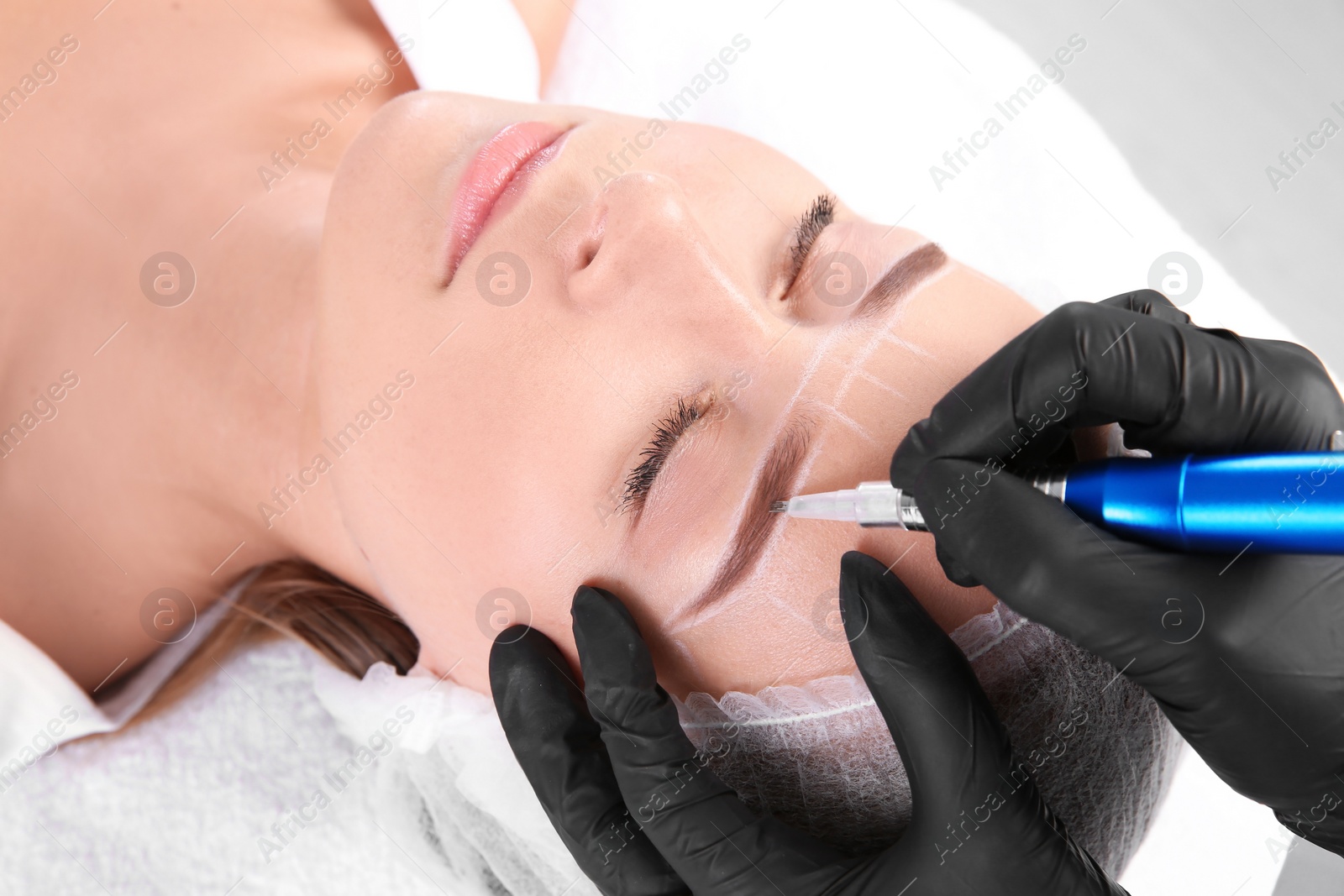 Photo of Young woman undergoing eyebrow correction procedure in salon