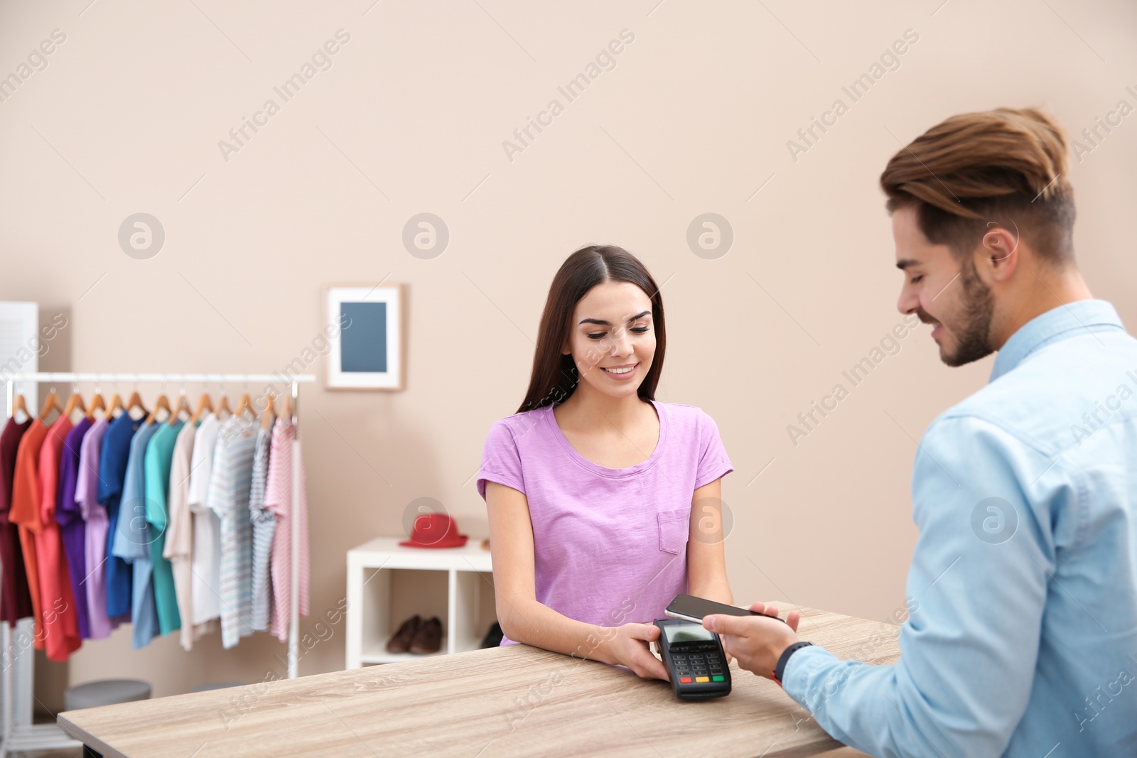 Photo of Man using terminal for contactless payment with smartphone in shop