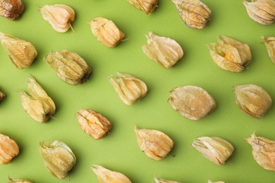 Ripe physalis fruits with calyxes on light green table, flat lay