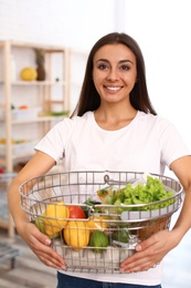 Photo of Young woman with shopping basket full of products in grocery store
