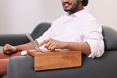 Photo of Man using smartphone on sofa armrest wooden table at home, closeup