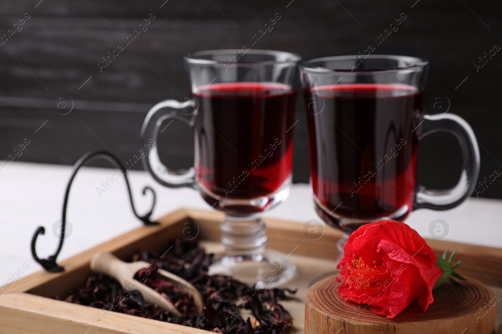 Photo of Beautiful Hibiscus flower and delicious tea on wooden tray, closeup