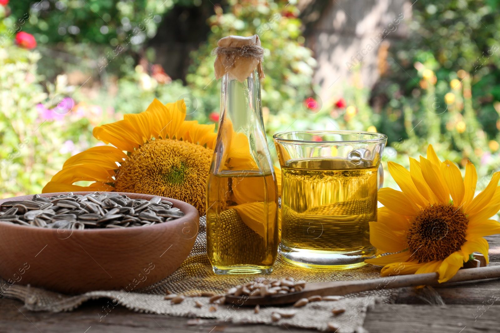 Photo of Sunflower oil and seeds on wooden table outdoors