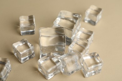 Photo of Crystal clear ice cubes on beige background, closeup