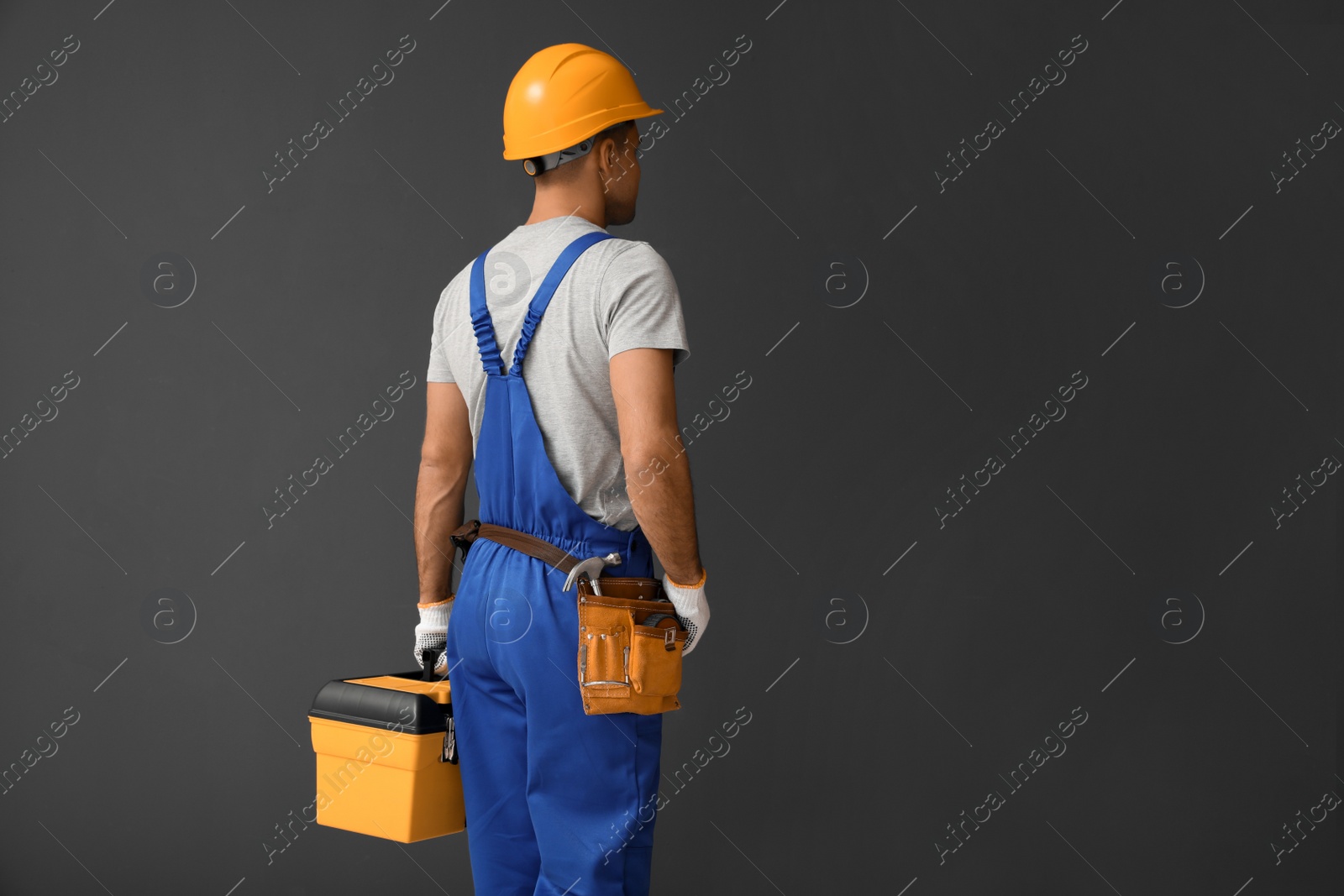 Photo of Handsome carpenter with tool box on dark background. Space for text