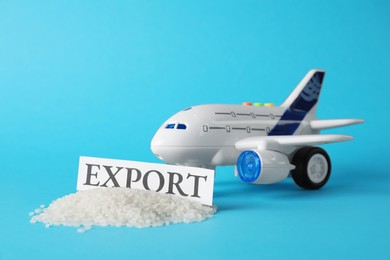 Photo of Card with word EXPORT, toy plane and rice grains on light blue background. Export concept