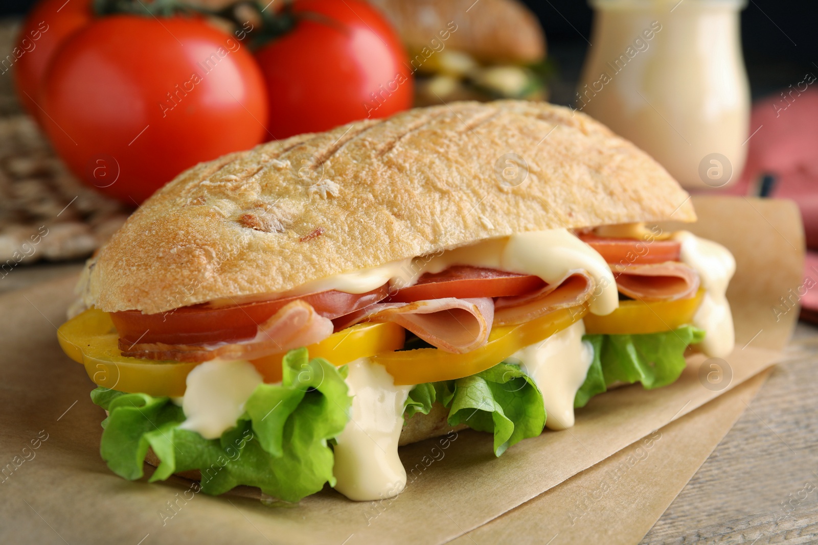 Photo of Delicious sandwich with vegetables, ham and mayonnaise served on wooden table, closeup