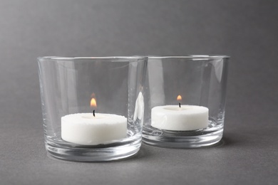 Photo of Candles in glass holders on grey background