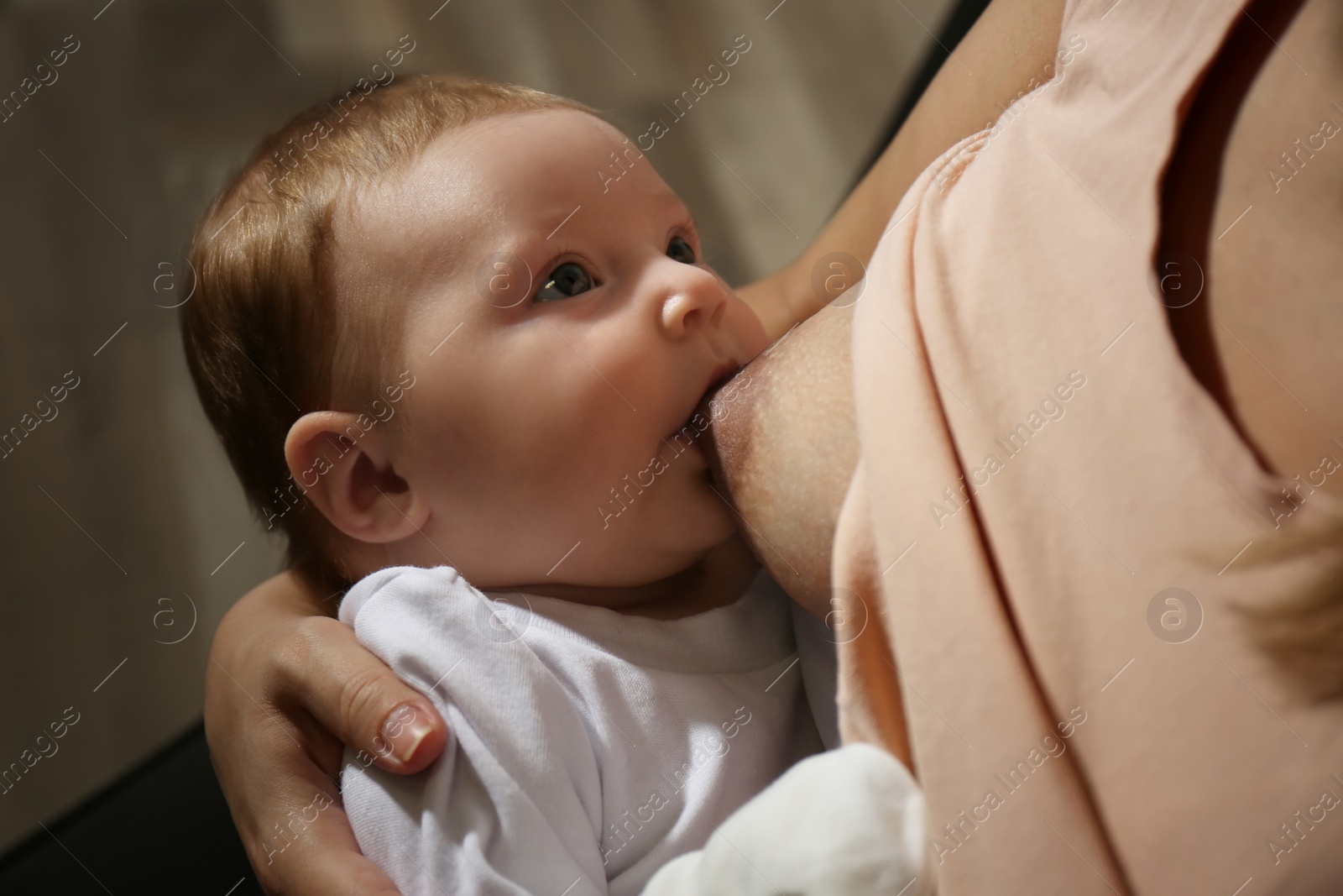 Photo of Young woman breast feeding her little baby at home, closeup