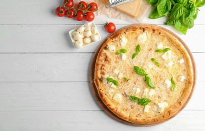 Delicious pizza with cheese and basil on wooden background, top view