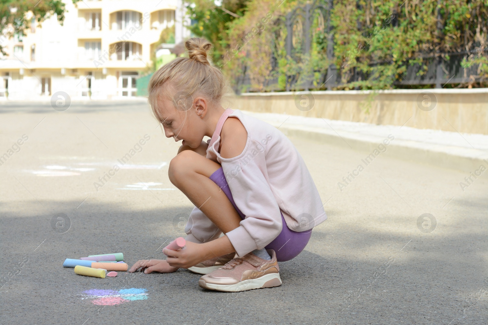 Photo of Little child drawing butterfly with chalk on asphalt