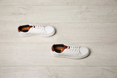 Photo of Pair of stylish sports shoes on white wooden floor, above view