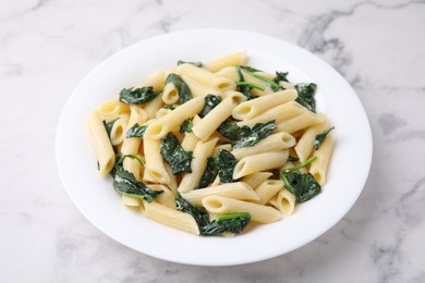 Photo of Tasty pasta with spinach and sauce on white marble table