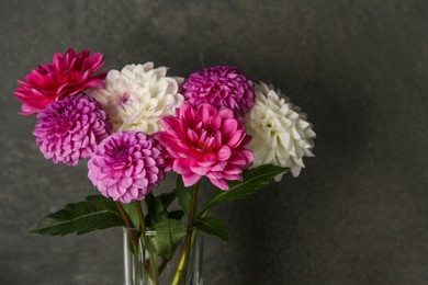 Photo of Bouquet of beautiful Dahlia flowers near dark grey wall. Space for text