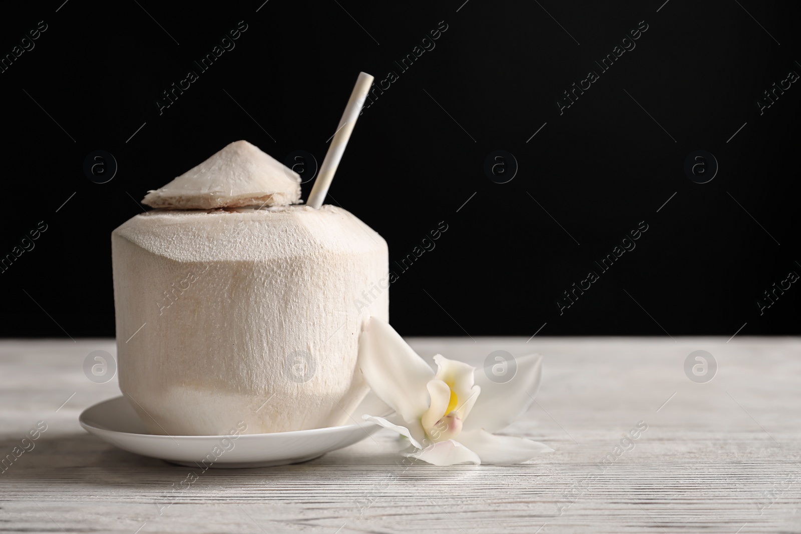 Photo of Fresh coconut drink in nut on table against black background