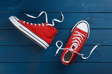 Pair of red sneakers on blue wooden table, flat lay