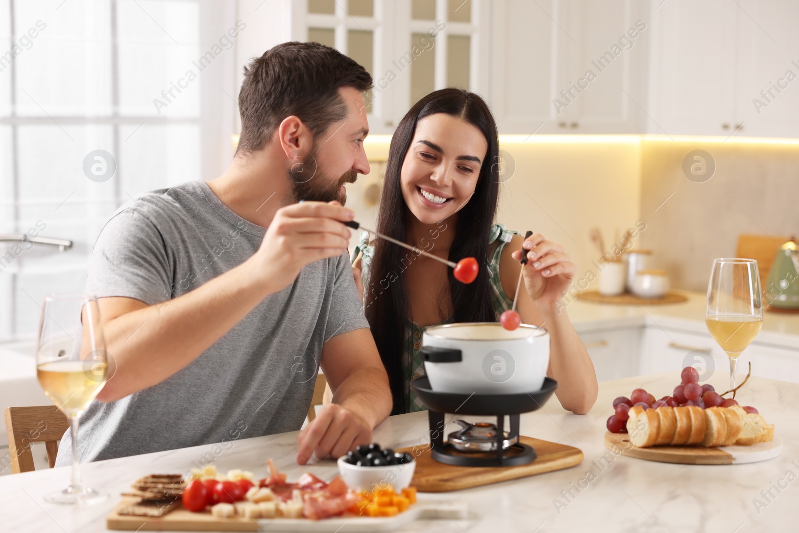 Photo of Affectionate couple enjoying fondue during romantic date in kitchen