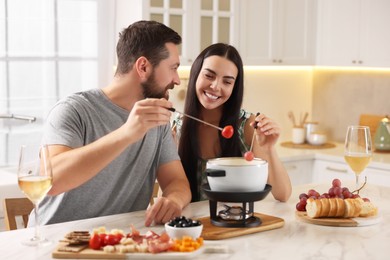 Affectionate couple enjoying fondue during romantic date in kitchen