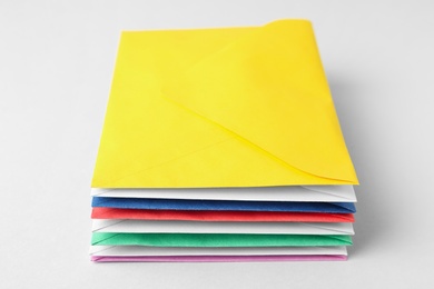 Photo of Stack of colorful paper envelopes on light background